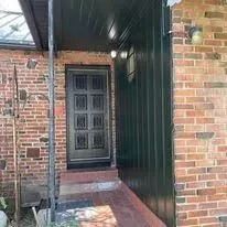 Brick front entry with a black door under a covered porch