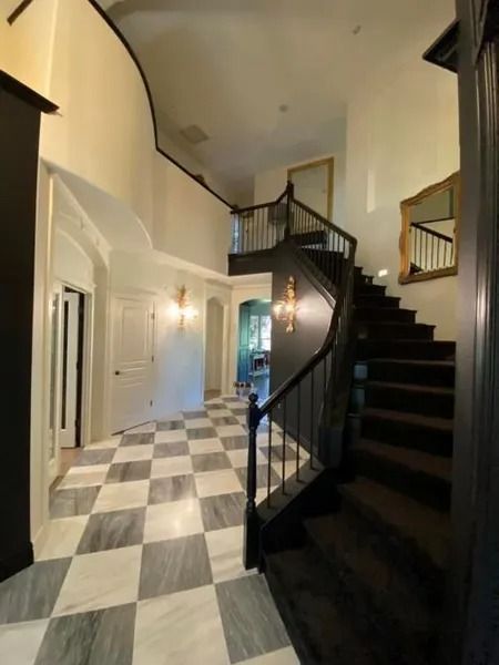 Spacious entry hall with black-and-white checkered floor, curved staircase, and high ceiling.