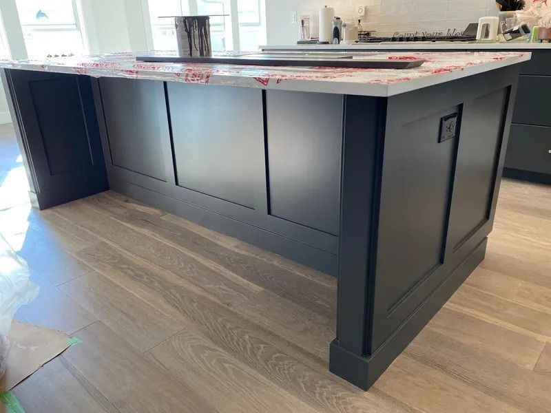Dark navy kitchen island with black countertop in a bright modern kitchen