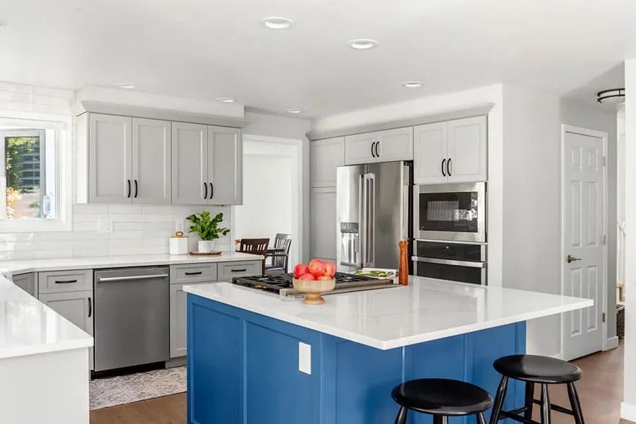 Bright white kitchen with stainless appliances and a blue island with stools