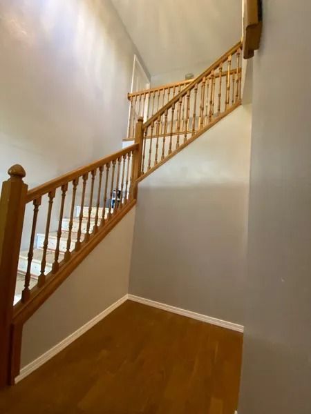 Wooden staircase with white walls and hardwood floor in a narrow hallway