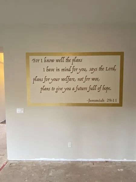 Living room wall with framed Bible verse quote in brown frame above white wainscoting
