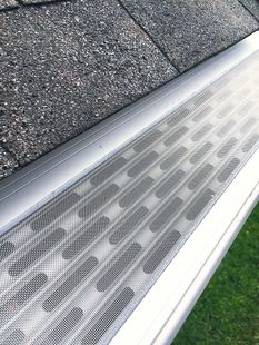 Gutter with metal mesh cover installed on a roof, protecting against debris.