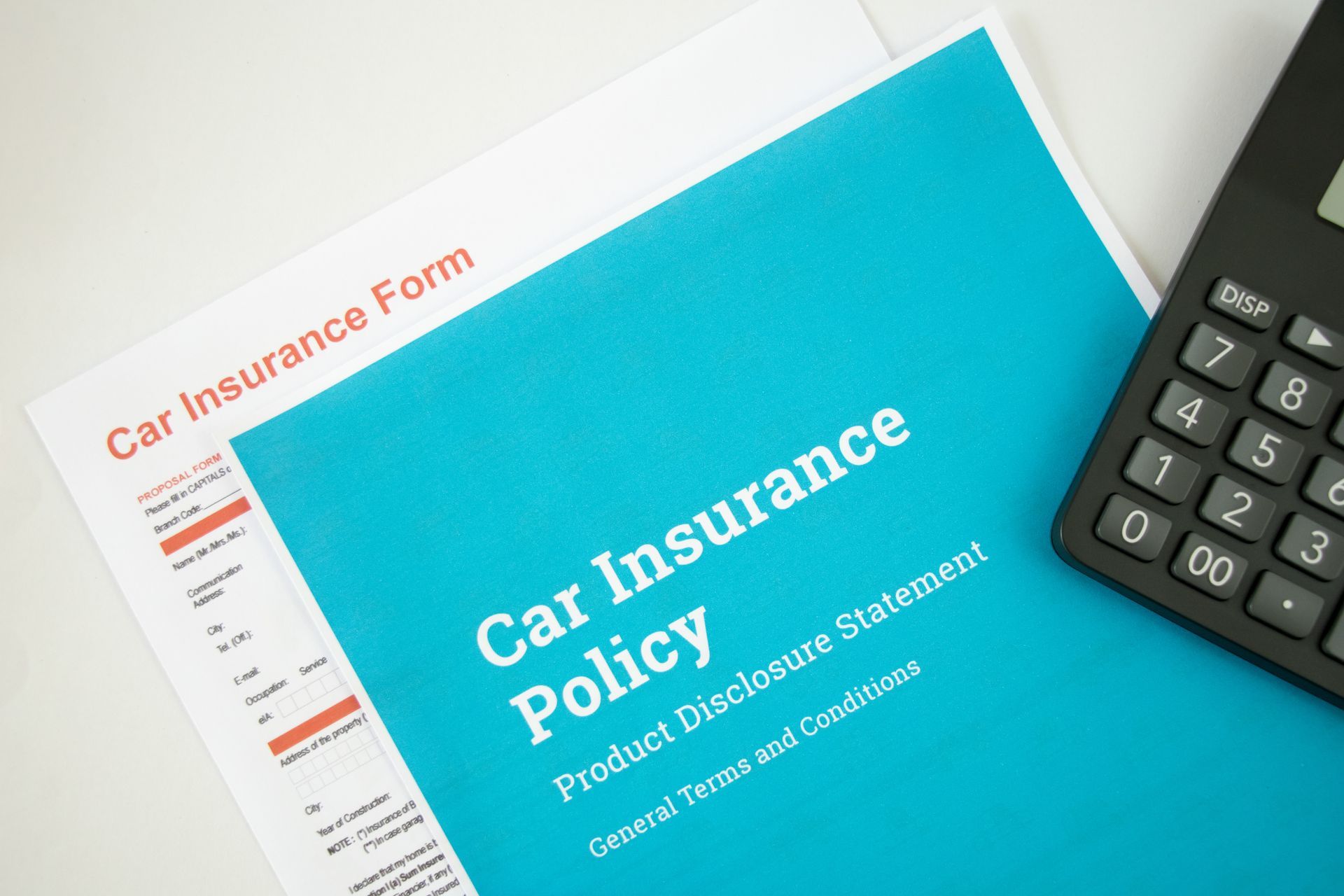 Car insurance policy document with calculator on a desk
