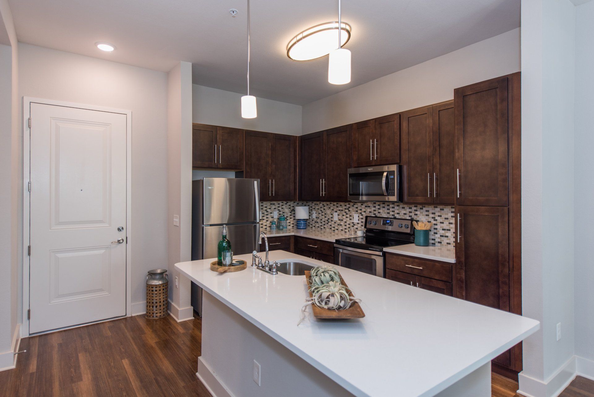 Modern kitchen with dark wood cabinets, stainless steel appliances, white quartz countertops, and an island at Silver Collection at Carl D. Silver Parkway in Fredericksburg, VA.