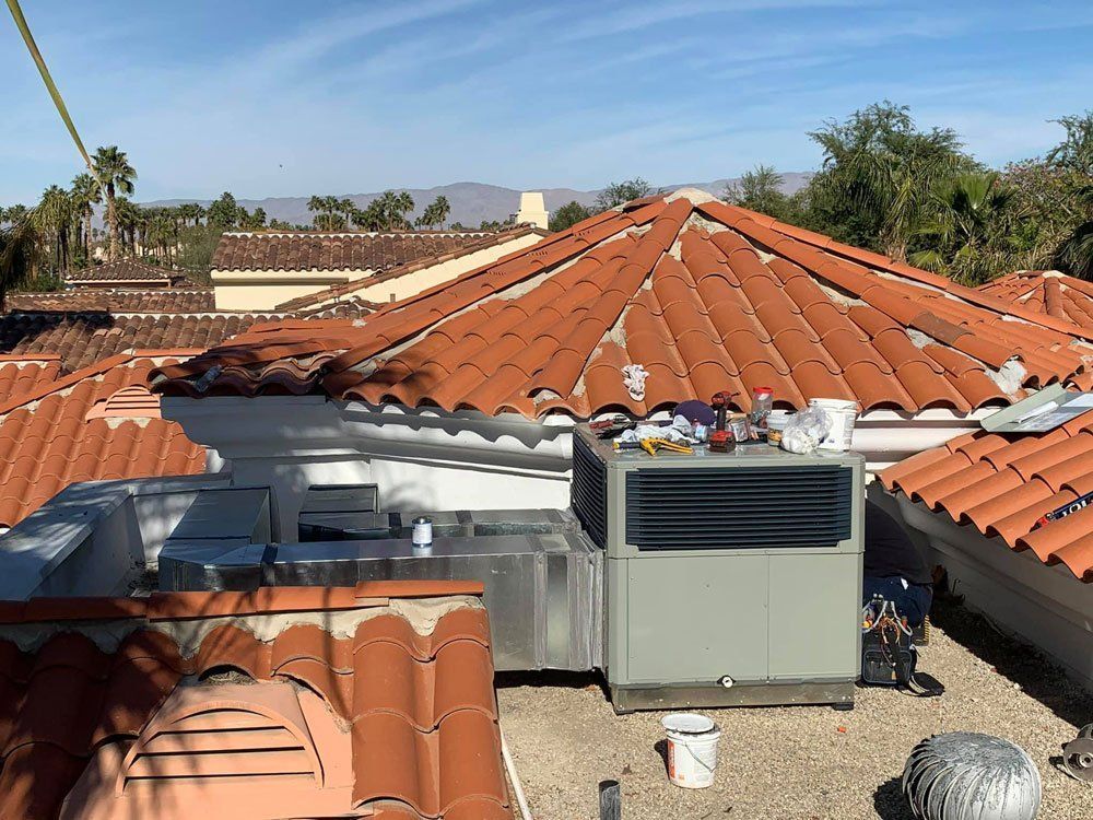 A large air conditioner is sitting on top of a tiled roof.