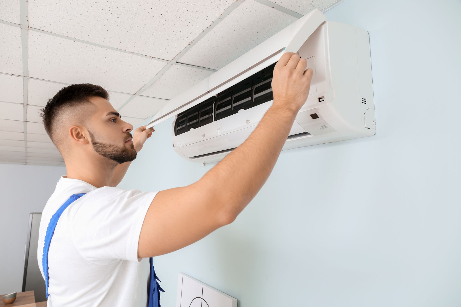 Male technician repairing air conditioner indoors. Male technician repairing air conditioner indoors.