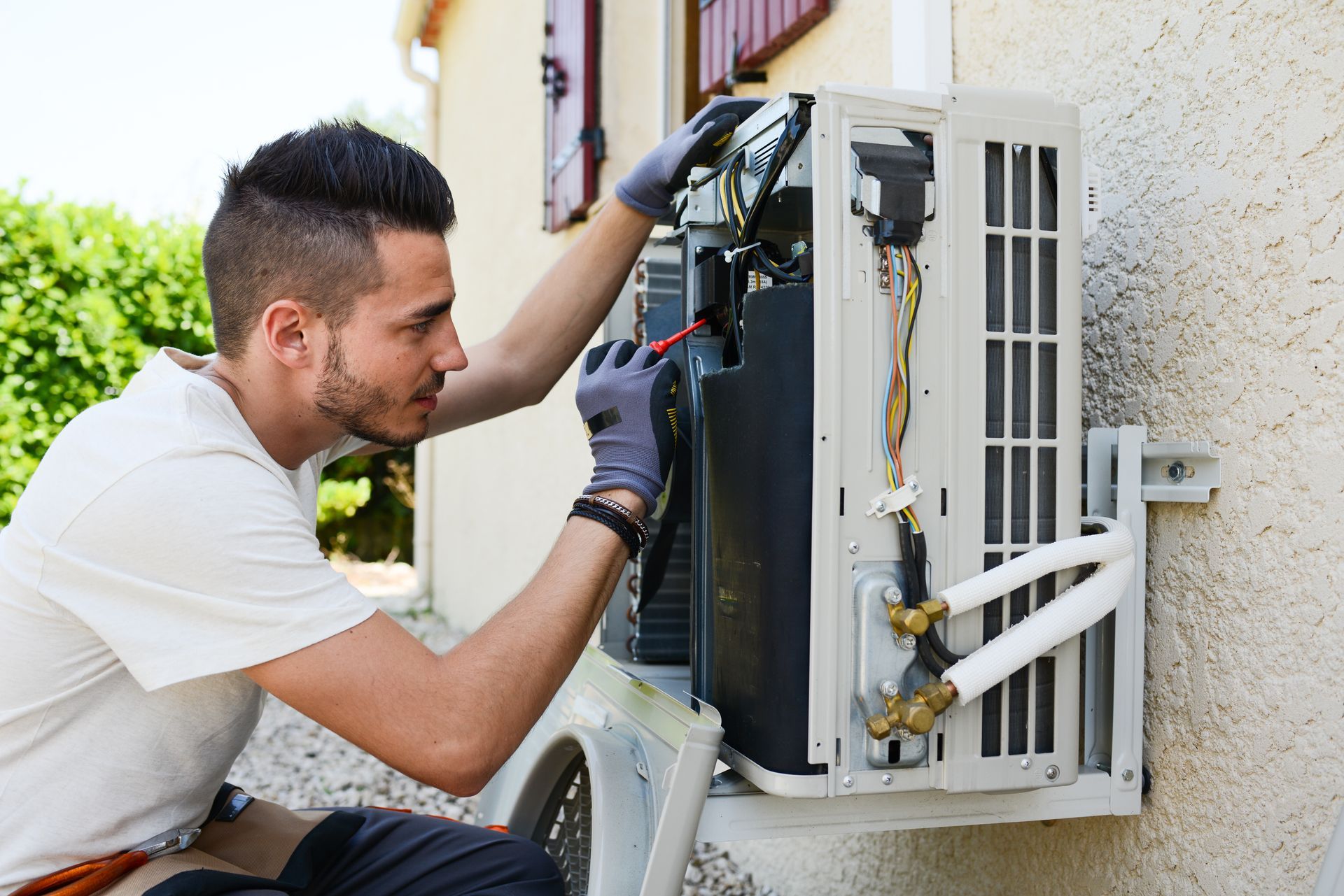 HVAC technician performing air conditioning repair on a home’s outdoor AC system.