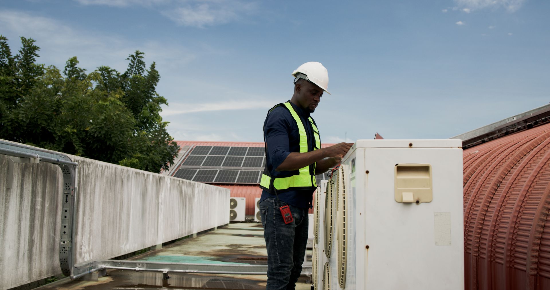 HVAC technician inspecting industrial gauges wearing safety gear on commercial equipment site. HVAC technician inspecting industrial gauges wearing safety gear on commercial equipment site.