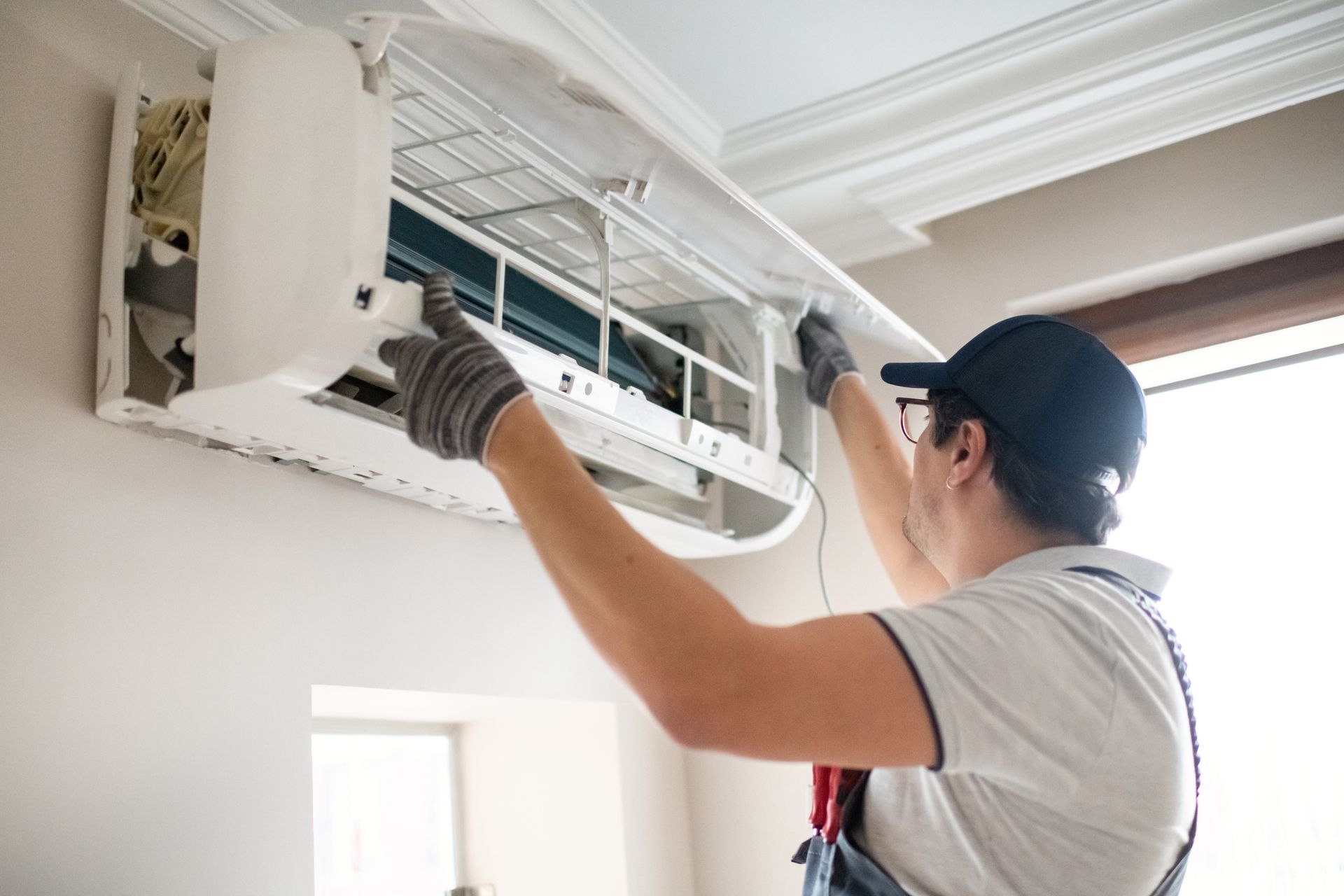 Person adjusts wall-mounted AC unit during installation, with internal components exposed.