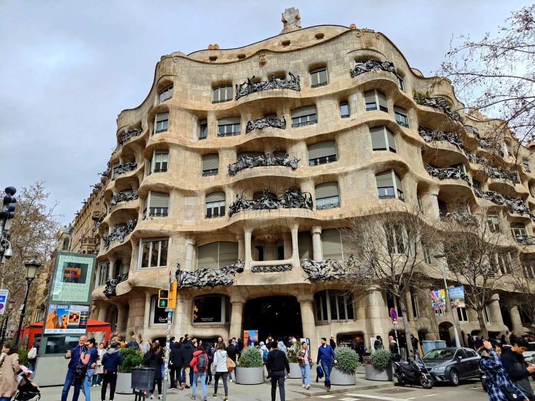 Casa Milà (La Pedrera) A large building with a lot of windows is surrounded by people