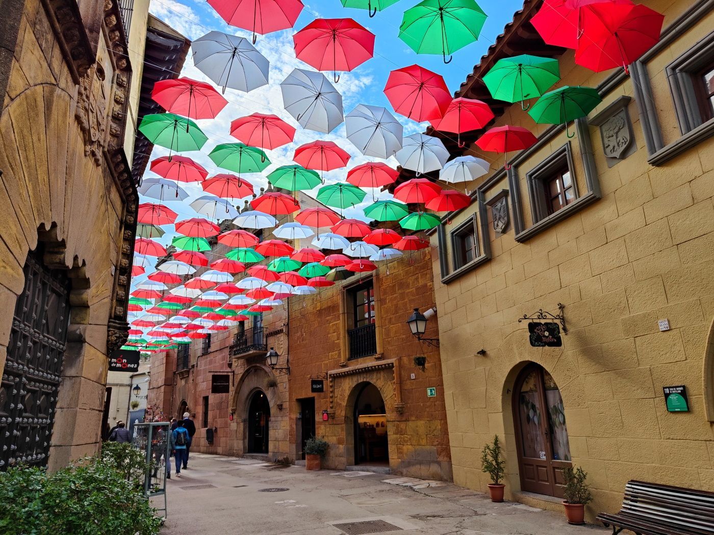 A row of umbrellas are hanging from the roof of a building