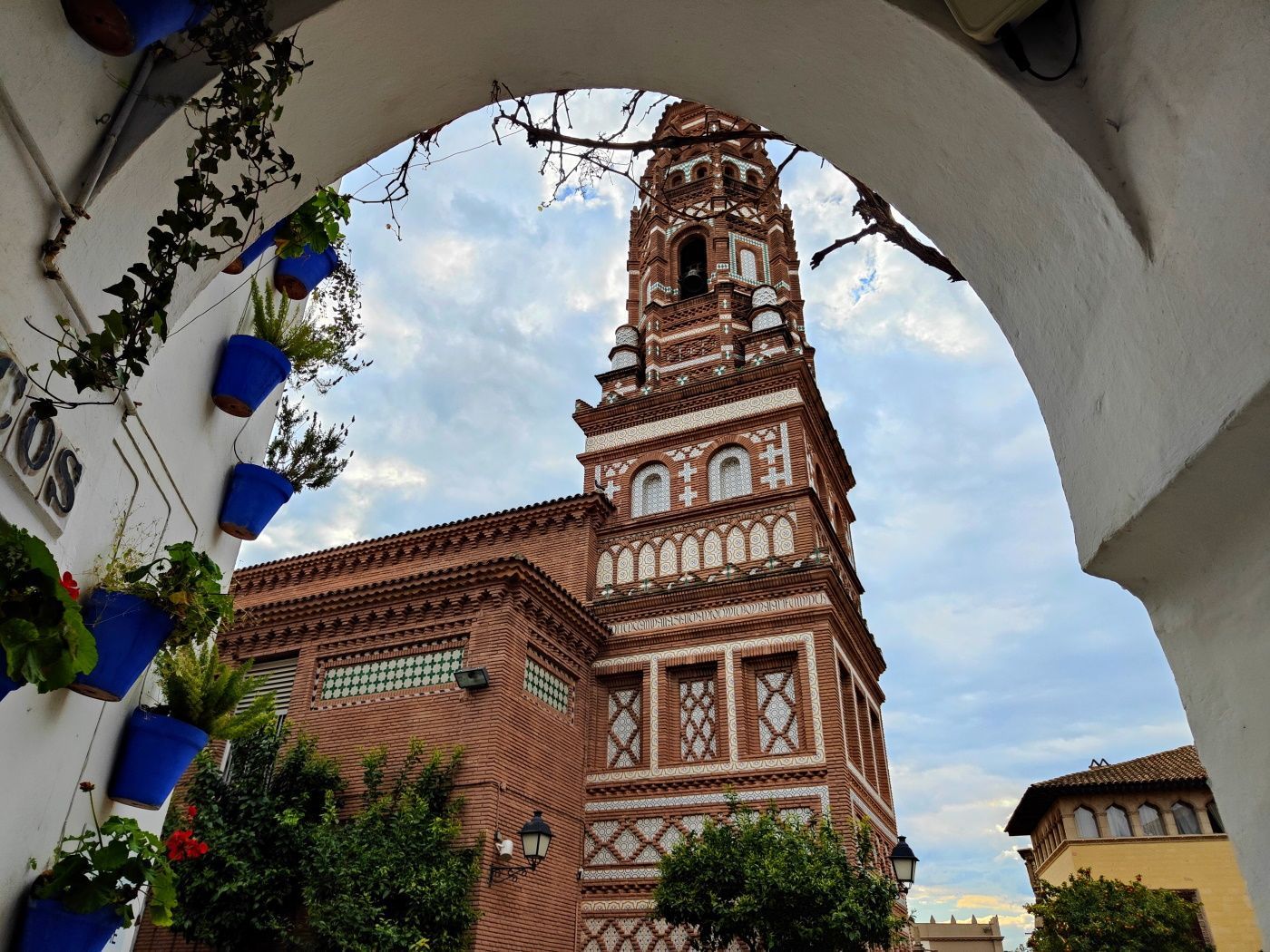 A brick building with a clock tower and potted plants on the side