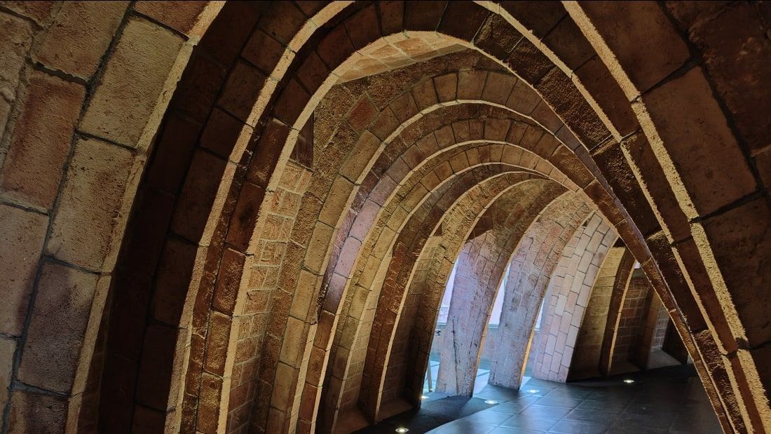 Barcelona Gaudi A brick tunnel with arches and lights on the floor