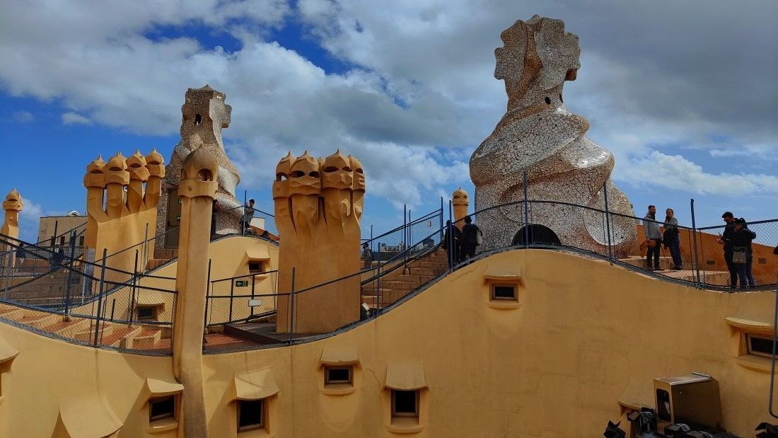 Gaudi Barcelona Aussicht A yellow building with a blue sky and clouds in the background