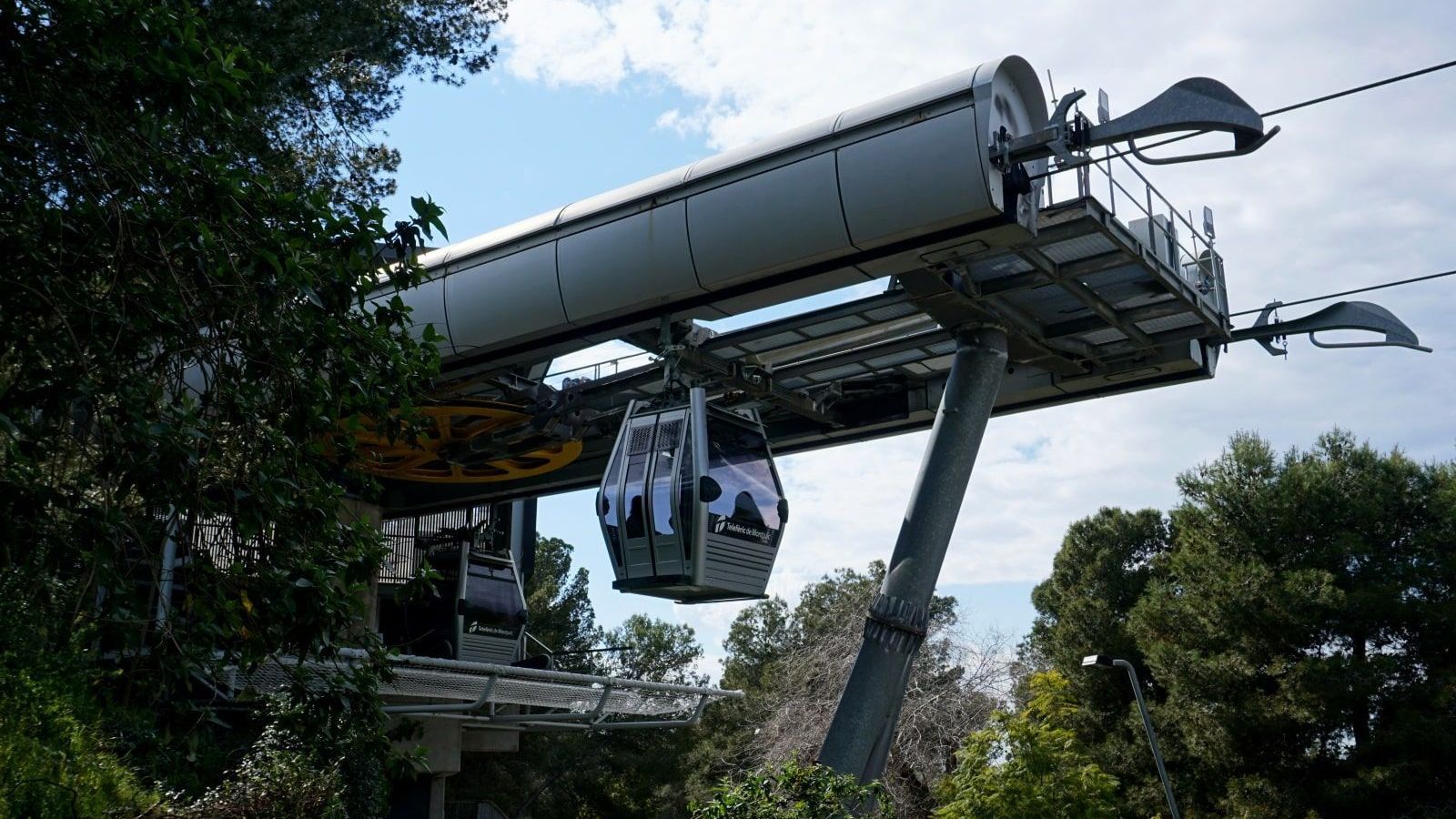 A cable car is going up a hill surrounded by trees
