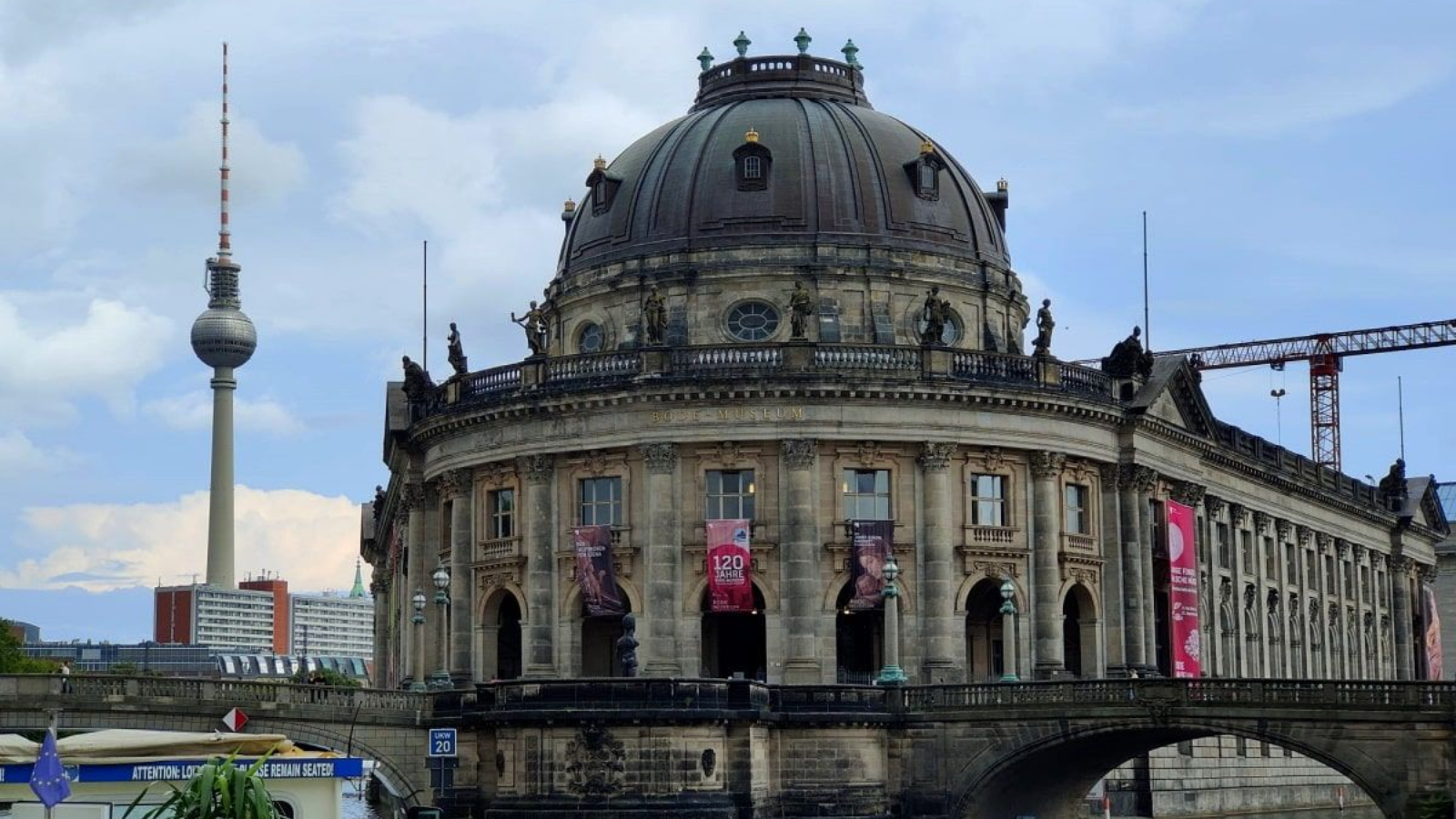 Schifffahrt Berlin Aussicht A large domed building in Berlin, with the TV Tower in the background, and a river in the foreground.