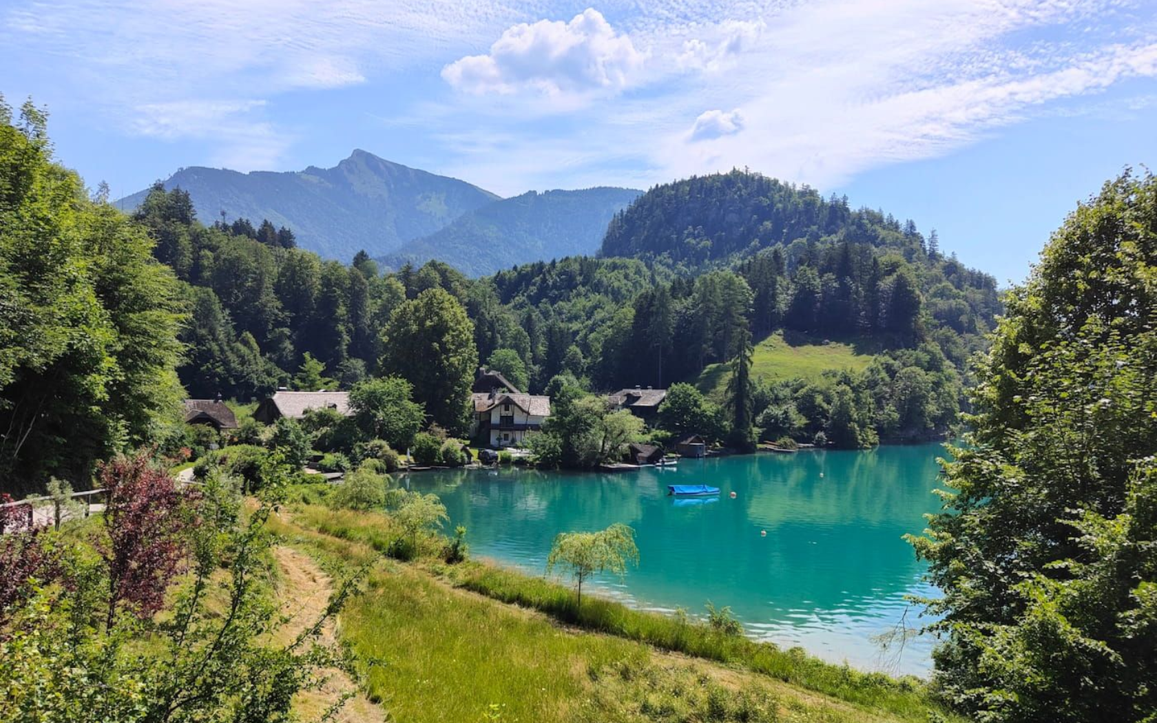 Brunnwinkl Turquoise lake beside forested hills and mountains under a bright blue sky