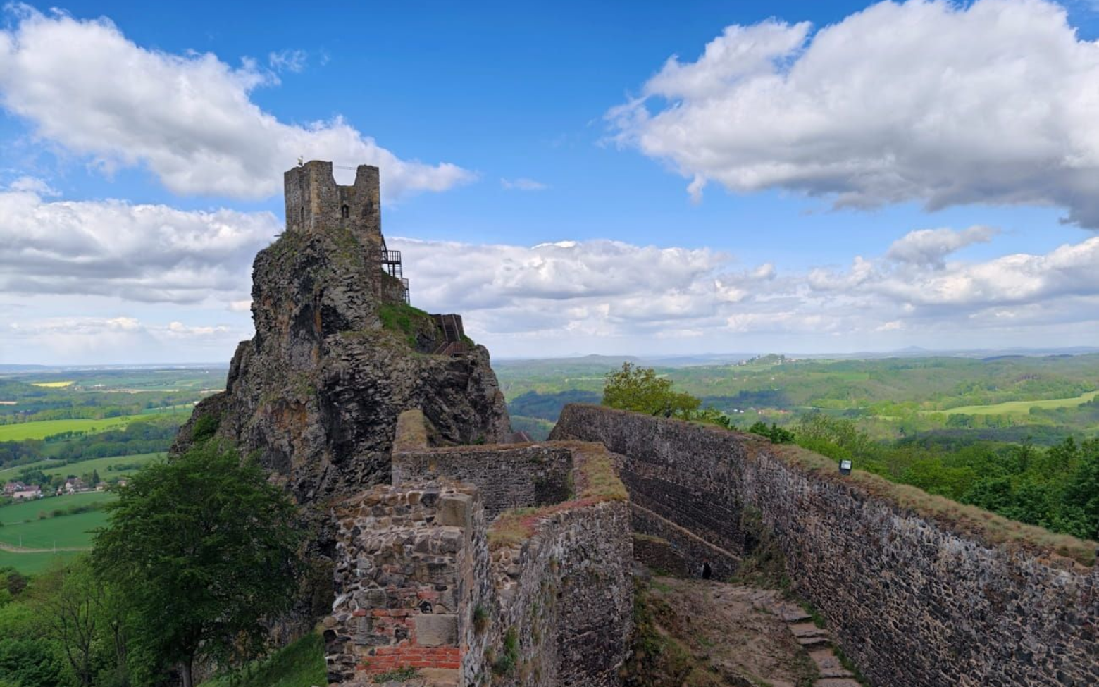 Böhmisches Paradies Trosky Ruins of a stone castle on a hill, with a winding wall overlooking green countryside under a cloudy sky