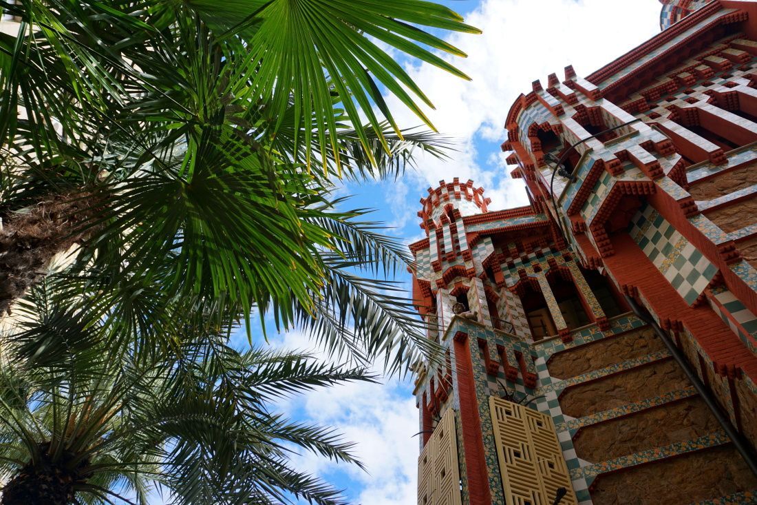 Looking up at a building with palm trees in front of it