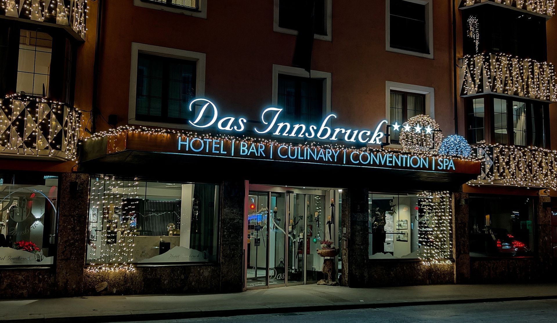 Der Eingang des Innsbruck Hotels bei Nacht mit beleuchtetem Schild und Dekorationen.