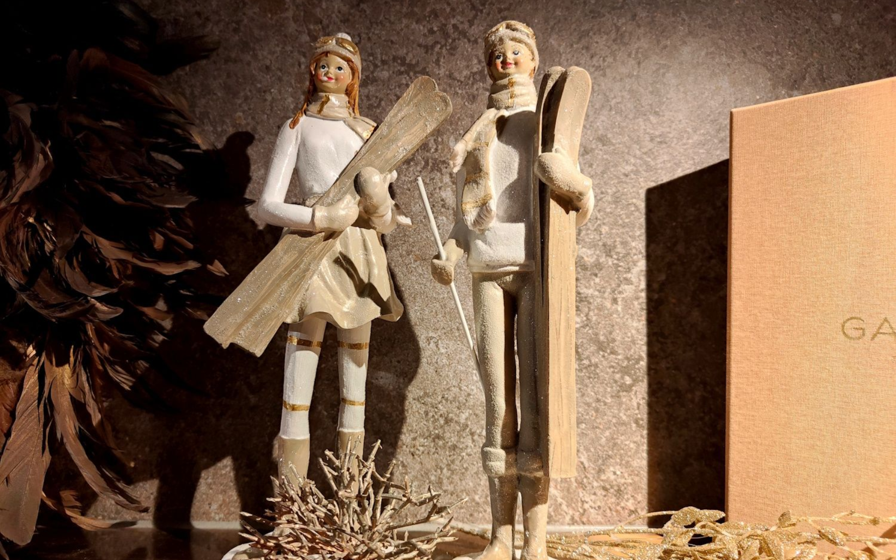 Das Innsbruck Two decorative figurines stand beside a brown surface, one holding a wooden prop.