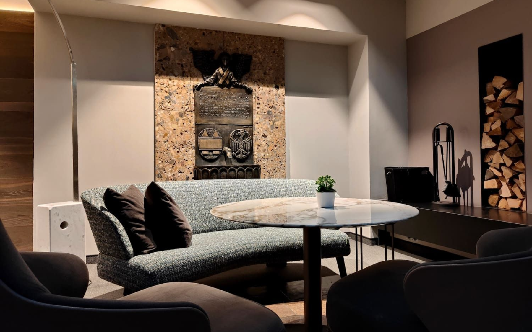 Das Innsbruck Cozy lounge area with curved blue sofa, round table, and decorative stone artwork.