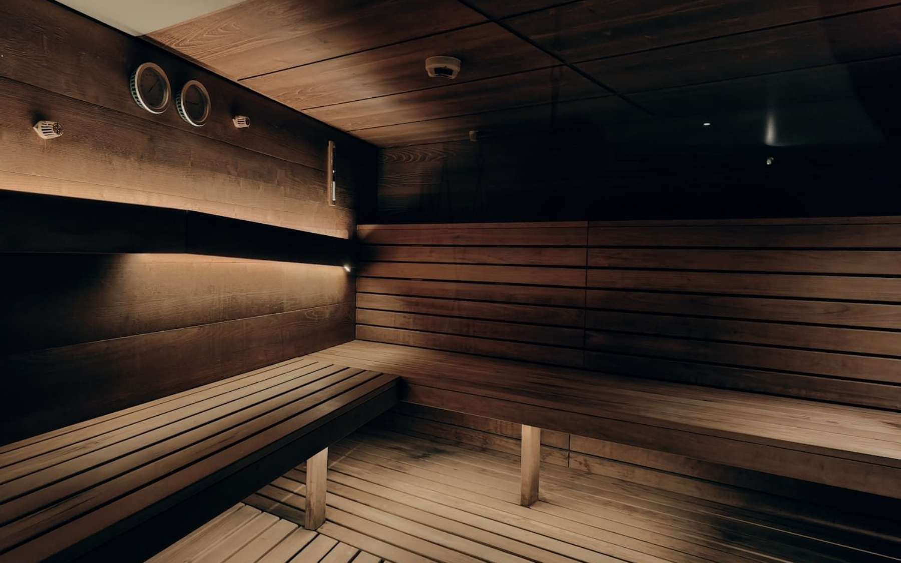 Das Innsbruck Sauna Wooden sauna interior with benches, dimly lit.