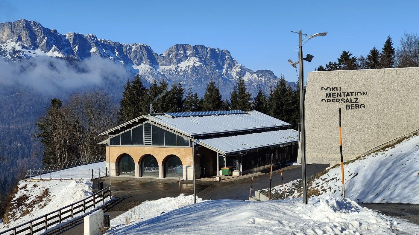 Dokumentation Obersalzberg A snowy landscape with a building in the foreground and mountains in the background