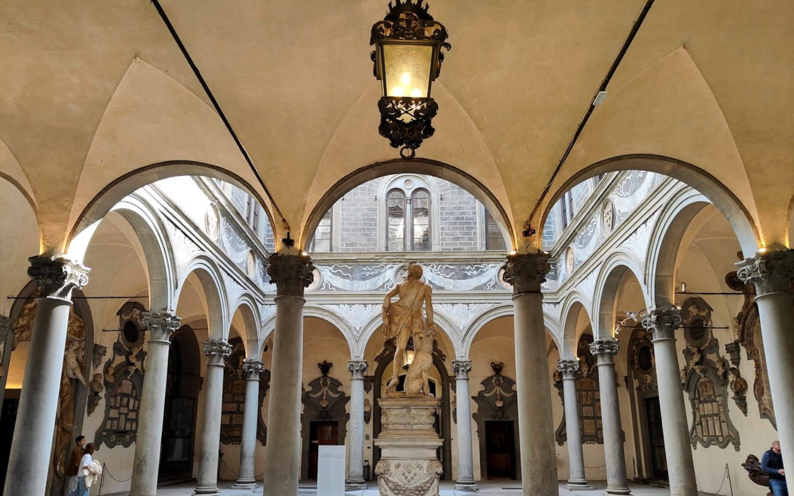 Medici Florenz Ornate courtyard with a central statue, stone arches, and decorative columns in a historical building.