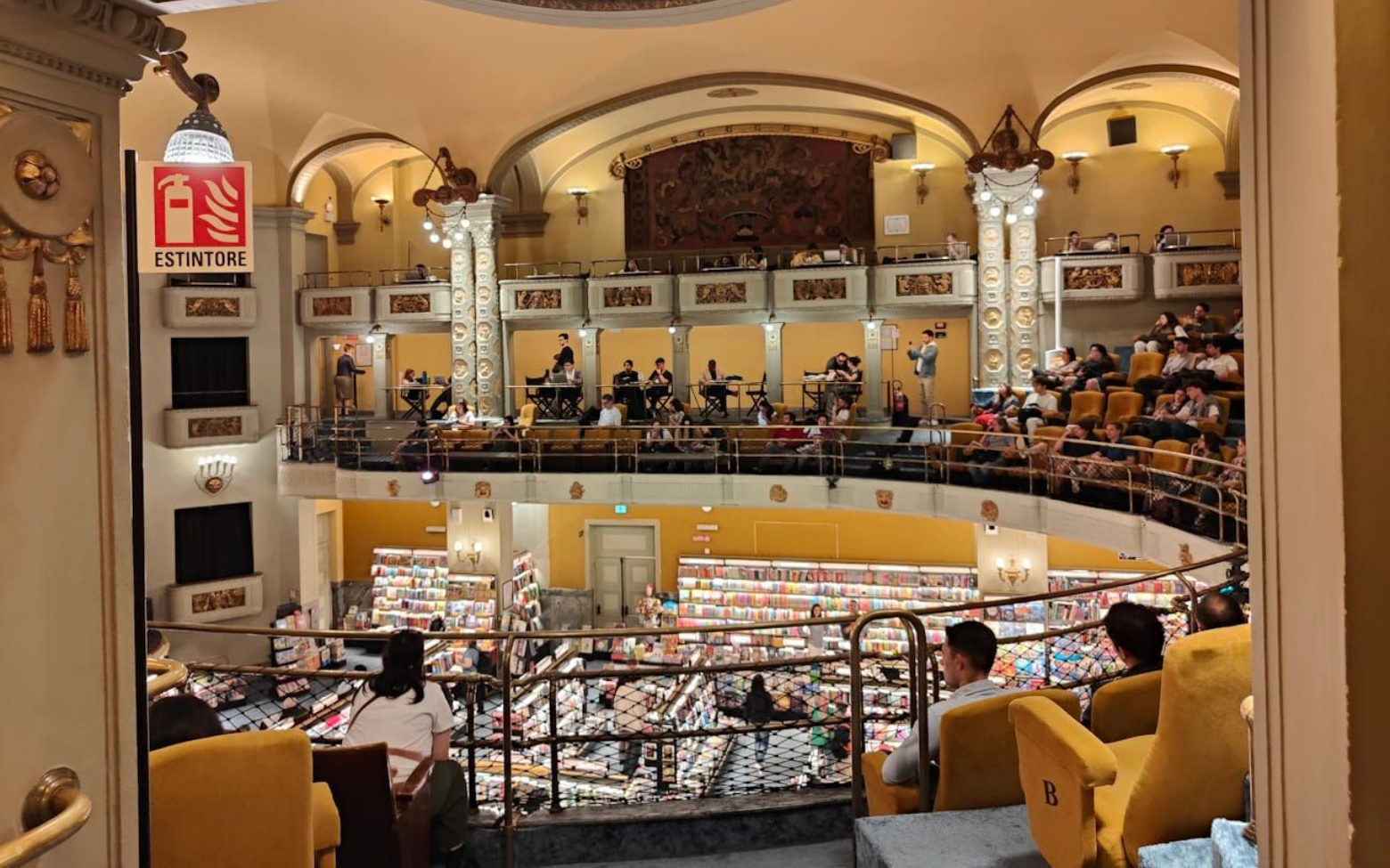 Odeon Florenz A bookstore, with shelves of books visible from the balcony seating of an ornate, historic hall.