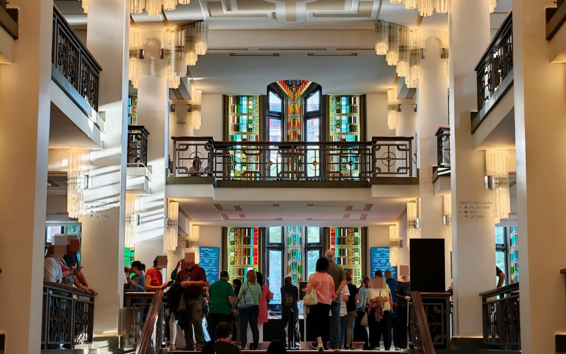 Friedrichstadt-Palast Berlin Elegant hotel lobby with chandeliers, stained-glass windows, and people gathered near the entrance