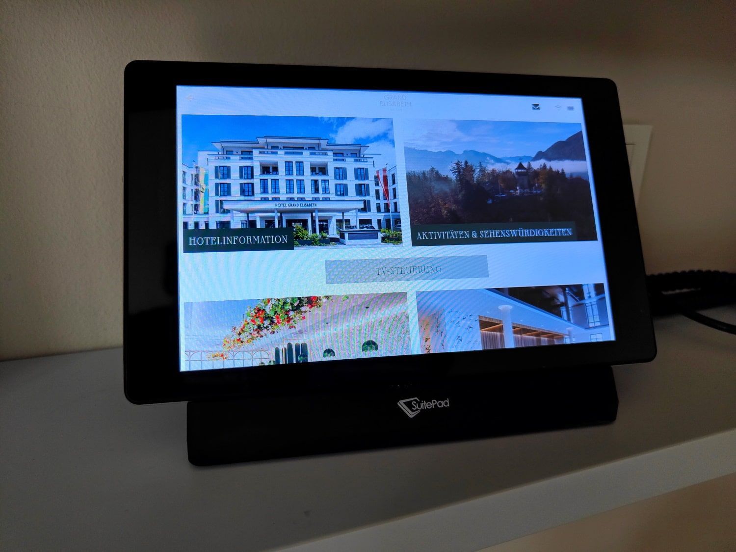 A touch screen displaying a hotel website, mounted on a black stand.