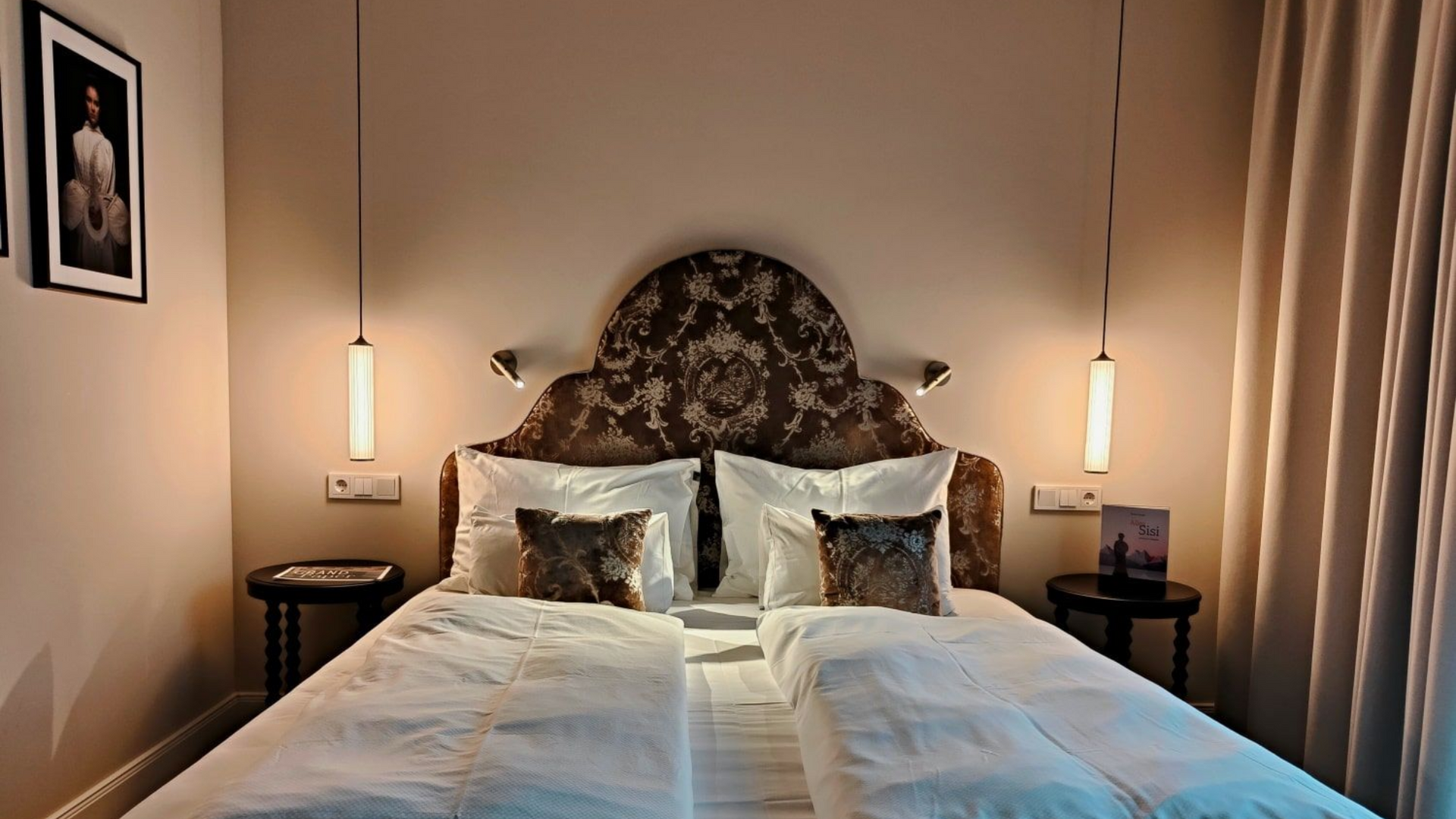 Grand Elisabeth Hotel Zimmer Bedroom with a large ornate headboard, two beds, bedside tables, and pendant lights.
