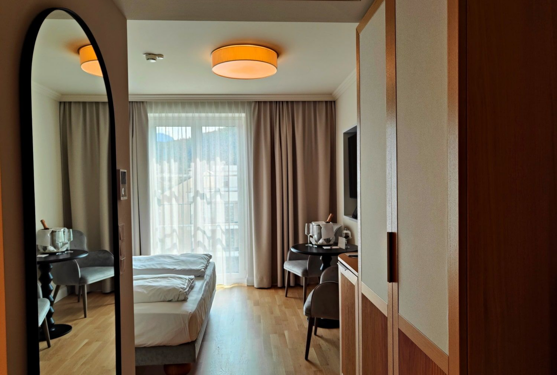 Grand Elisabeth Hotel Room Hotel room with a bed, table, chairs, and a full-length mirror on the left side.
