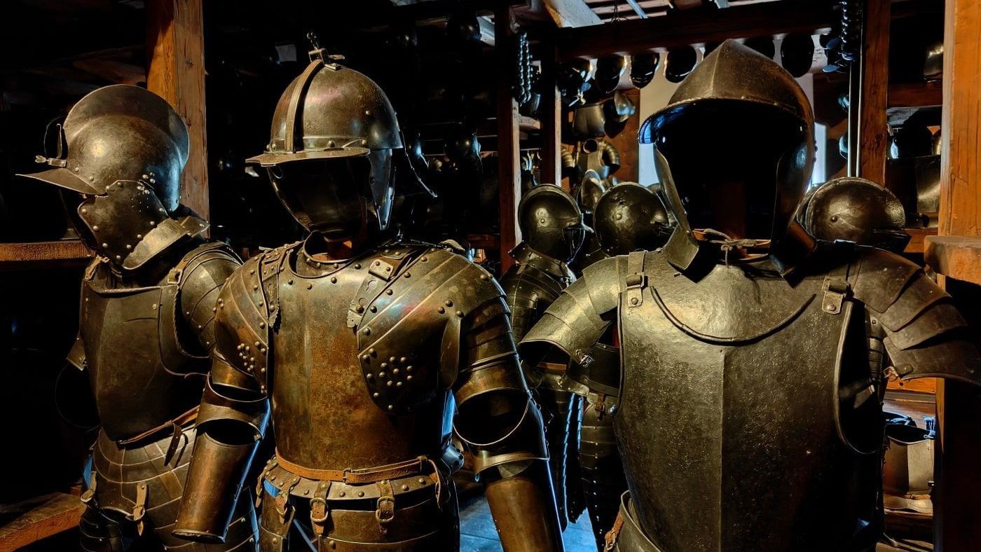 Graz Several suits of armor in a dimly lit room, likely a museum or storage space. They are dark metal, displayed upright.