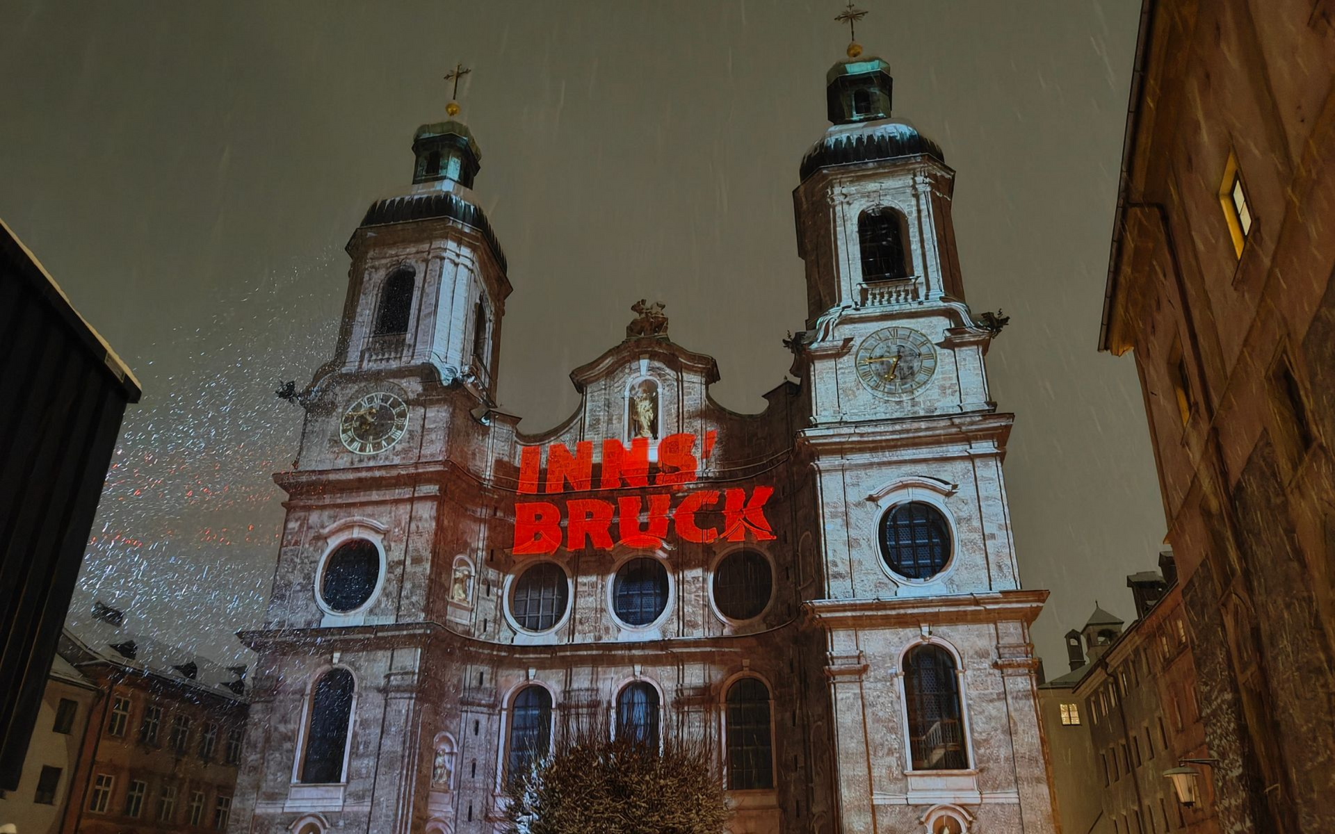 Der Innsbrucker Dom wurde bei Nacht beleuchtet, auf dessen Fassade der rote Schriftzug „Innsbruck“ projiziert wird.