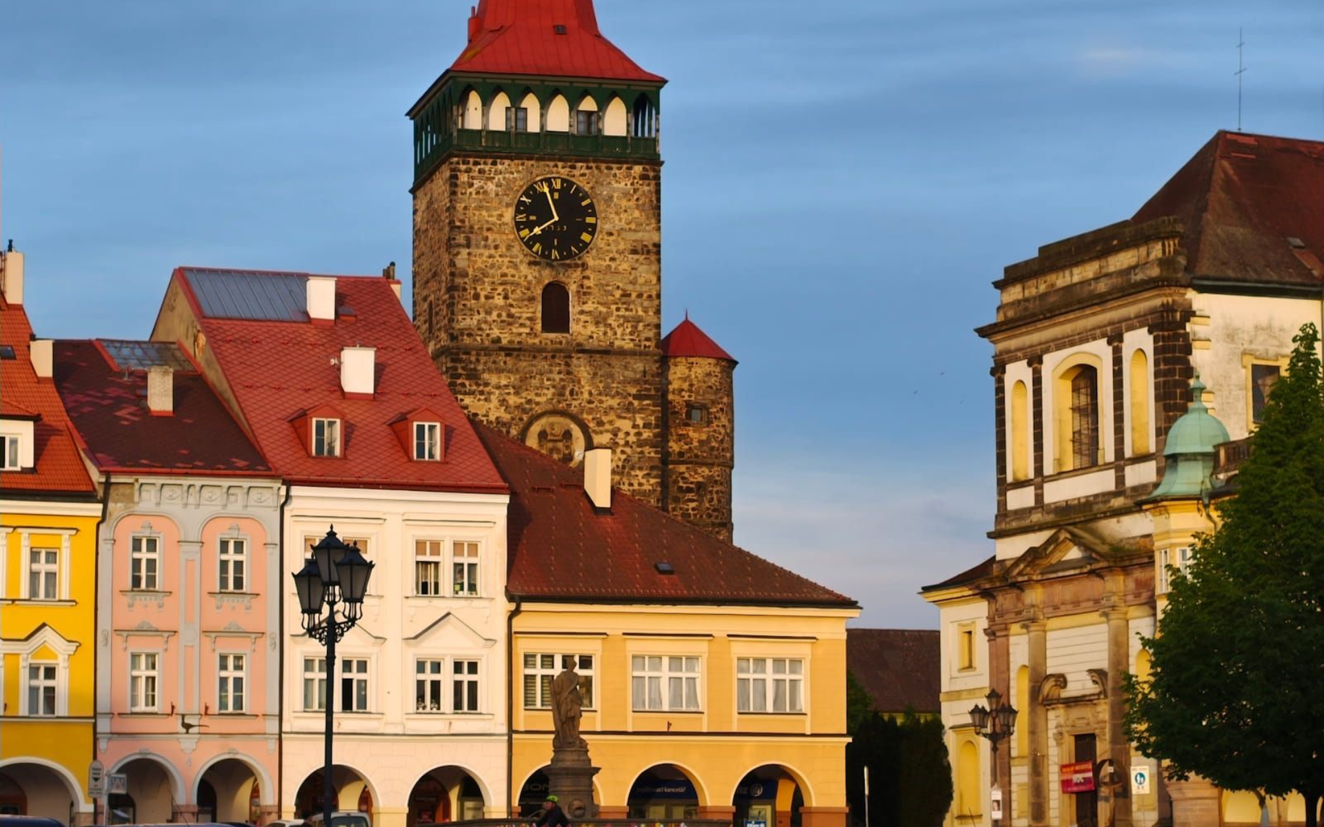 Jicín Hauptplatz Colorful historic buildings and a stone clock tower under a blue sky in a European town square