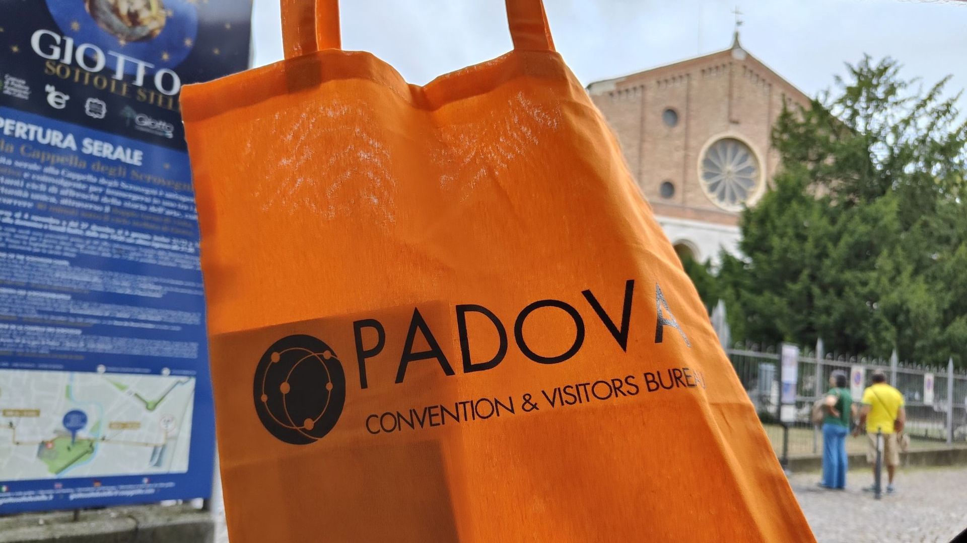Padova A person is holding an orange bag that says padova