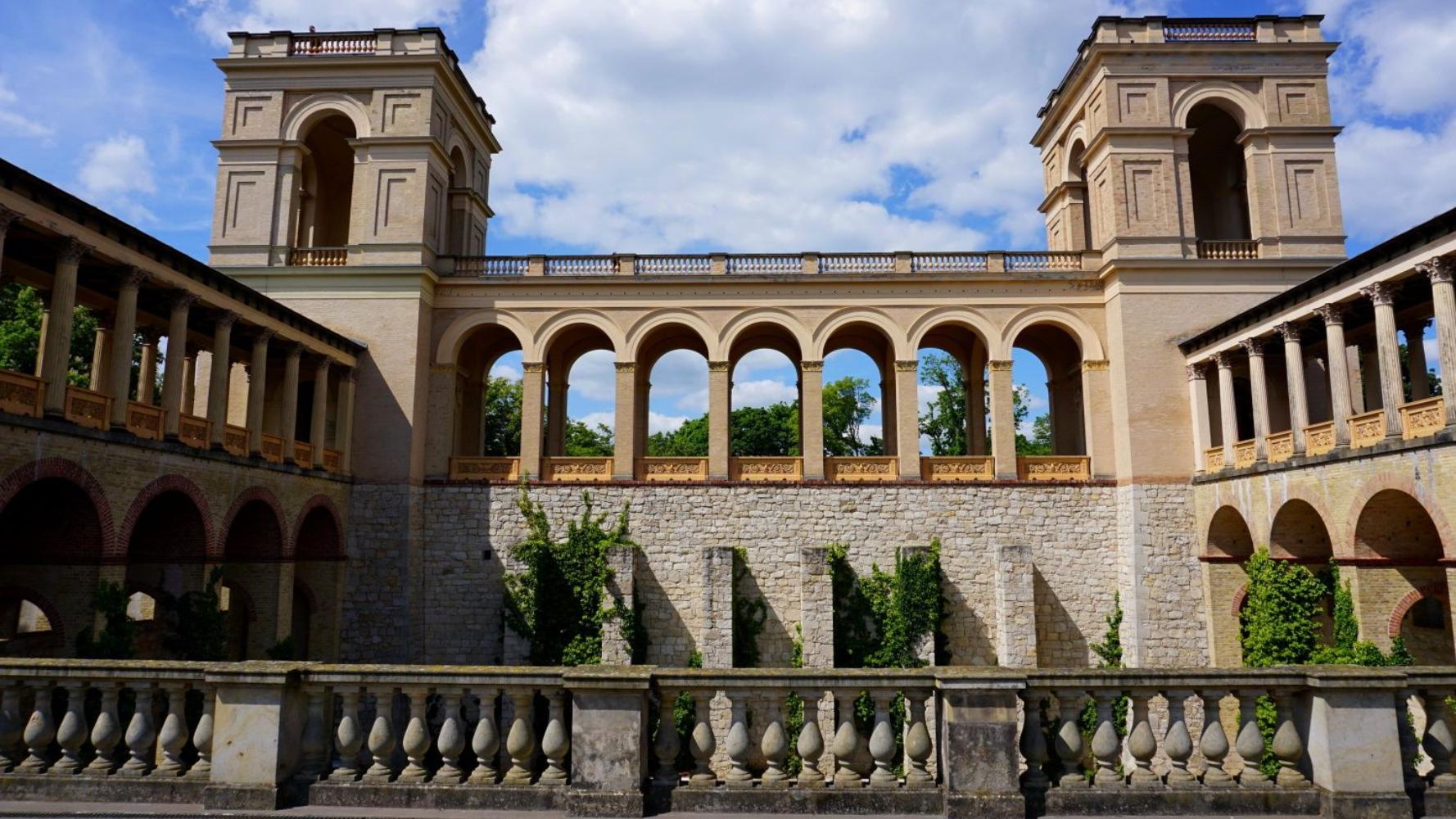 Belvedere Pfingstberg Potsdam Stone building with arched openings and two square towers against a cloudy sky.