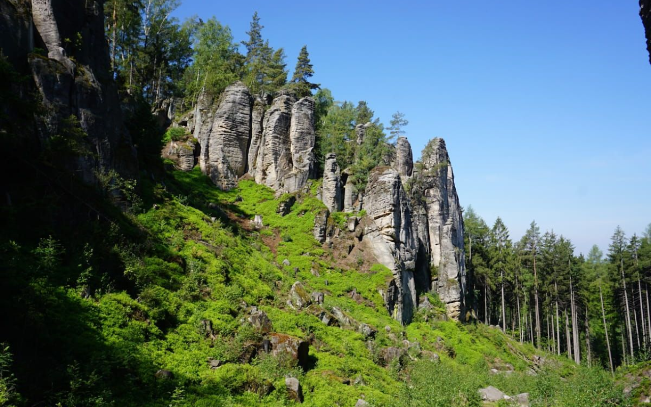 Prachow Rocky cliff face above a green forest hillside under a clear blue sky