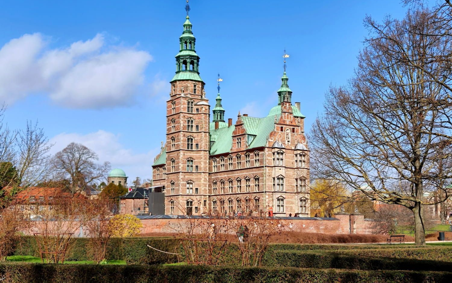 Schloss Rosenborg Historic brick castle with green copper spires behind bare trees on a sunny day. Schloss Rosenborg