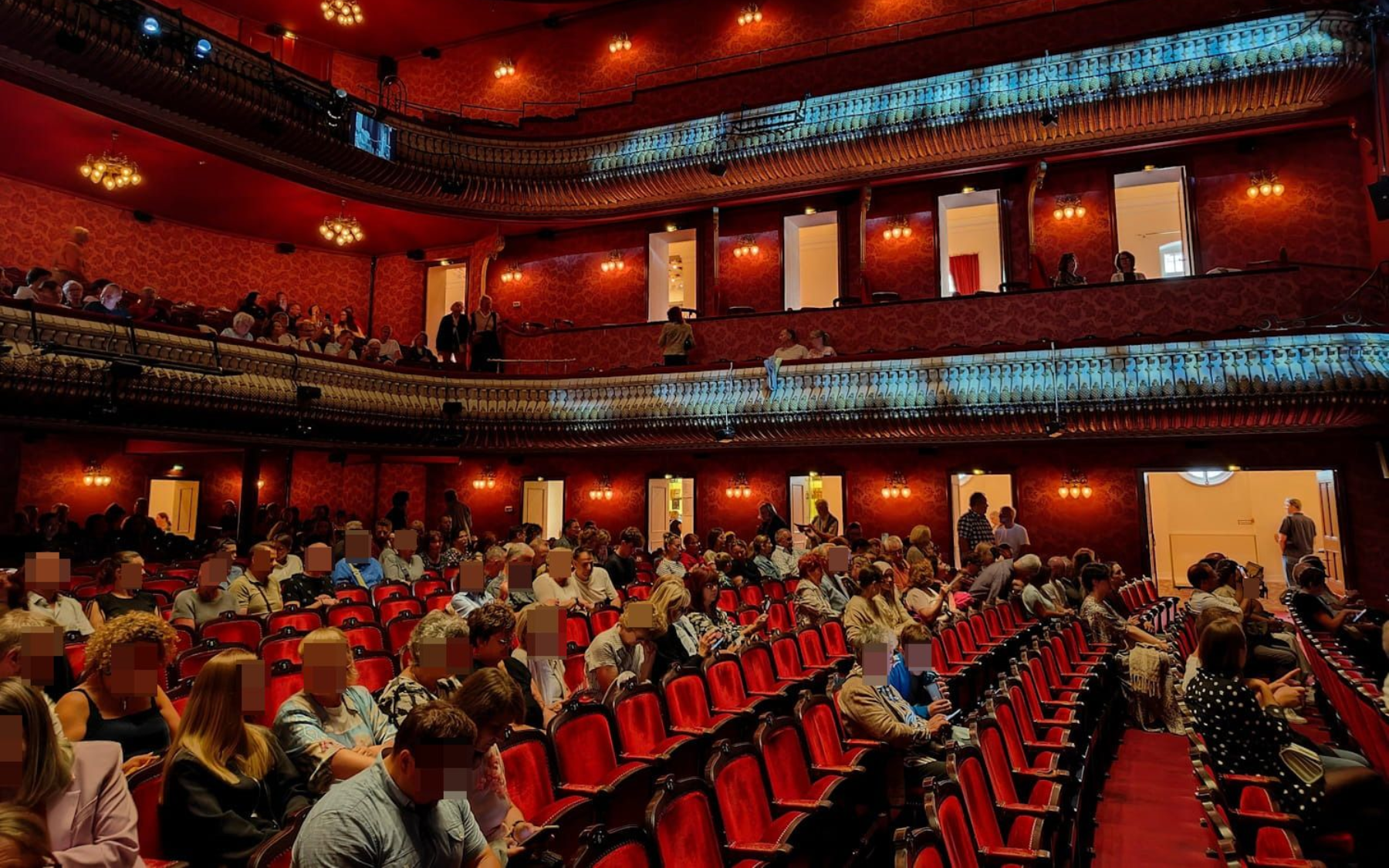 Theater des Westens in Berlin Crowded theater auditorium with red seats, warm lighting, and balconies filled with people