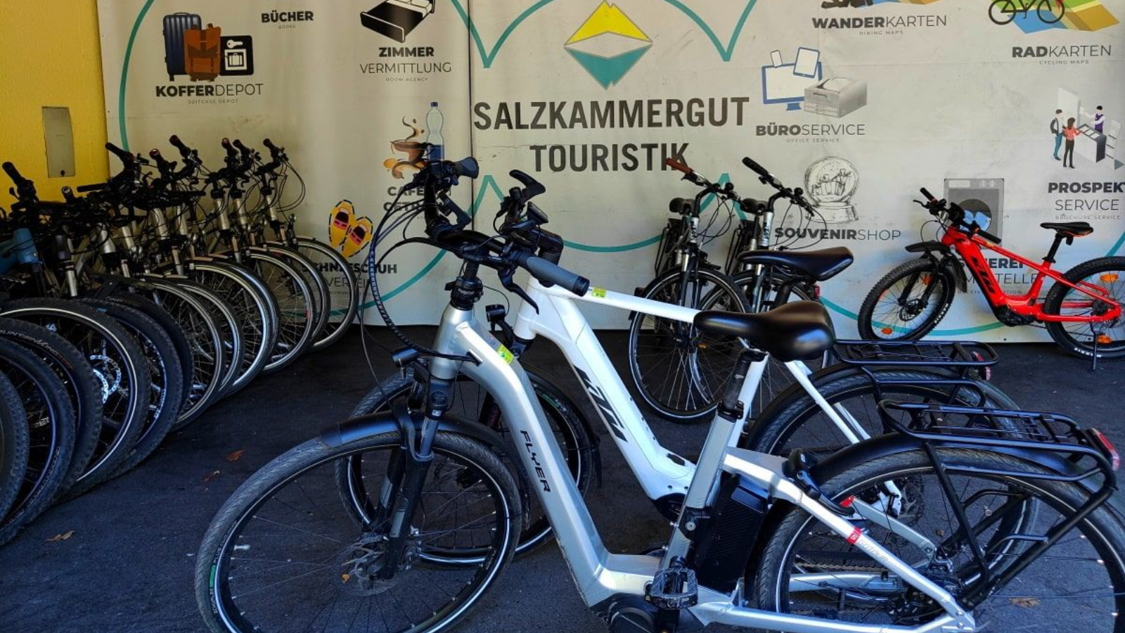 Salzkammergut Touristik Bikes parked in a rack at a tourism site with a sign for Salzkammergut Touristik.