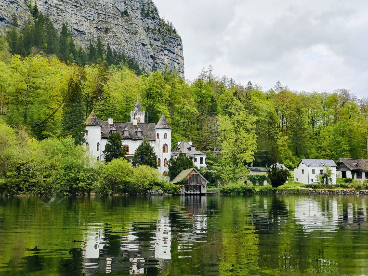 Hallstatt Schloss Grub A castle sits on the shore of a lake surrounded by trees