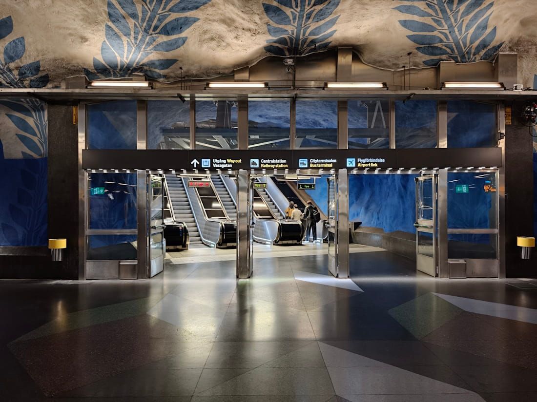 Empty transit station entrance with blue wall art and escalators in the background