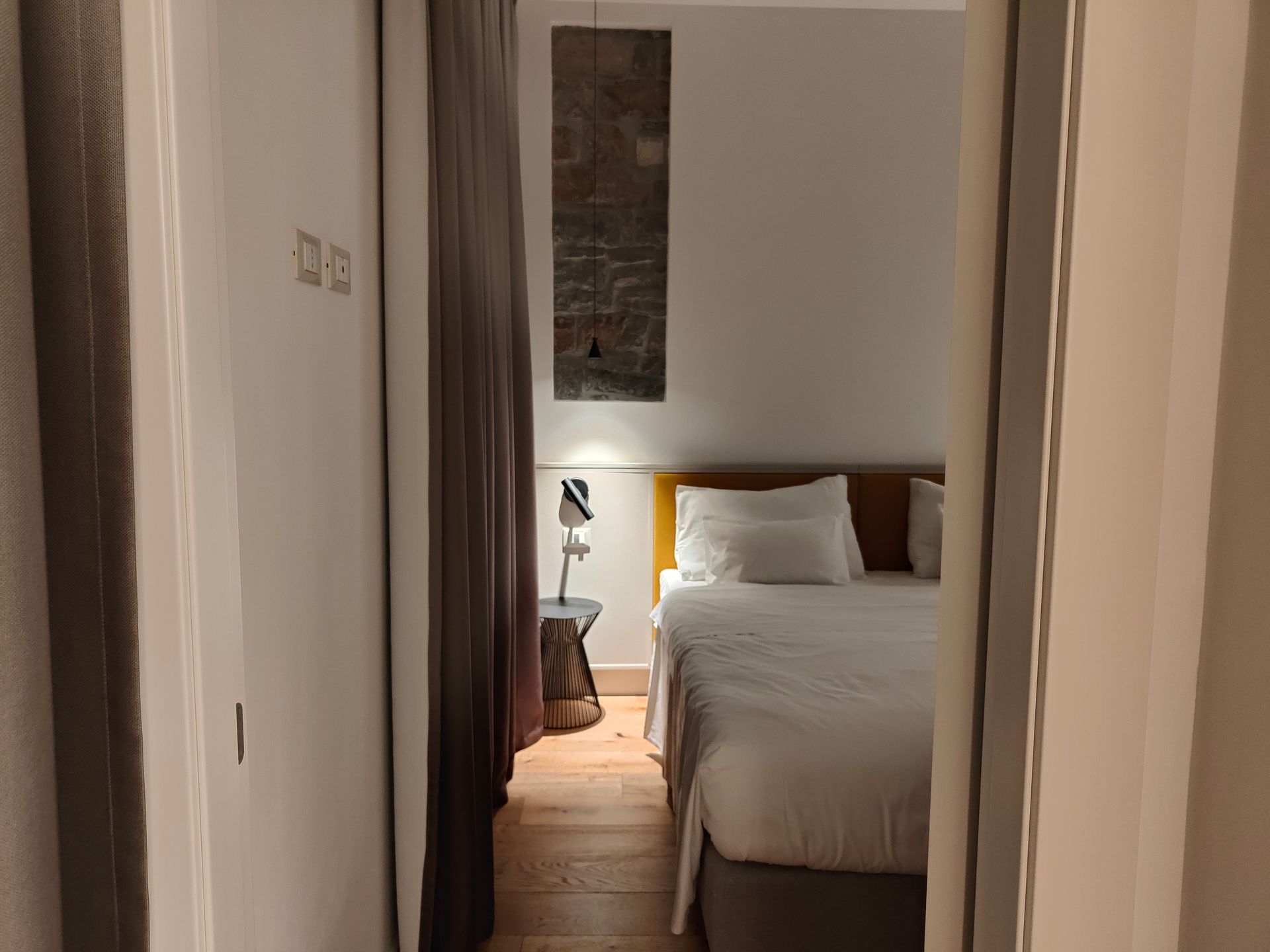Hallway view into a cozy bedroom with a bed, bedside lamp, and rug