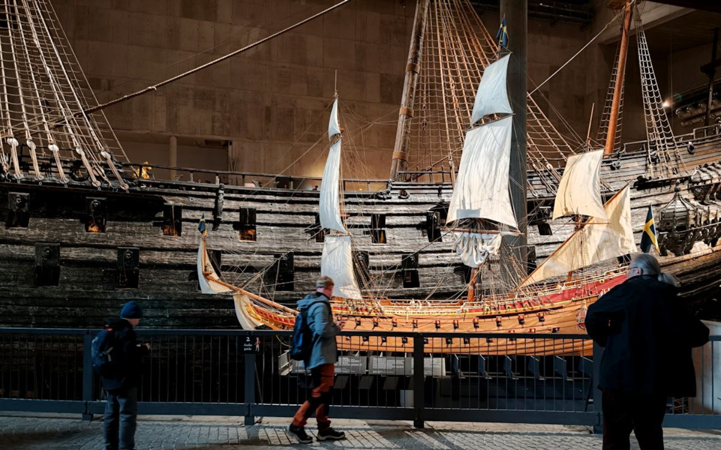 Vasa Museum Vasa Museum Stockholm.Model ship display in a museum, with visitors viewing a large wooden sailing ship under warm lights.