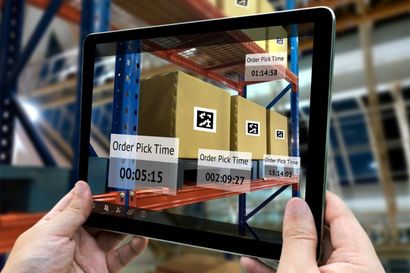 A person is holding a tablet with a picture of a warehouse on it.