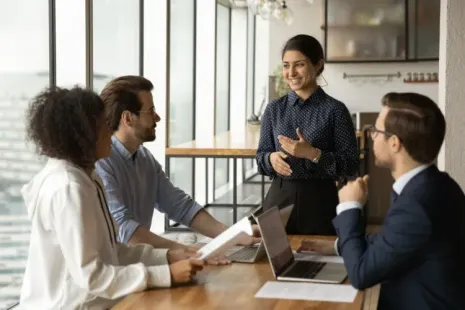 A group of people are sitting around a table having a meeting.
